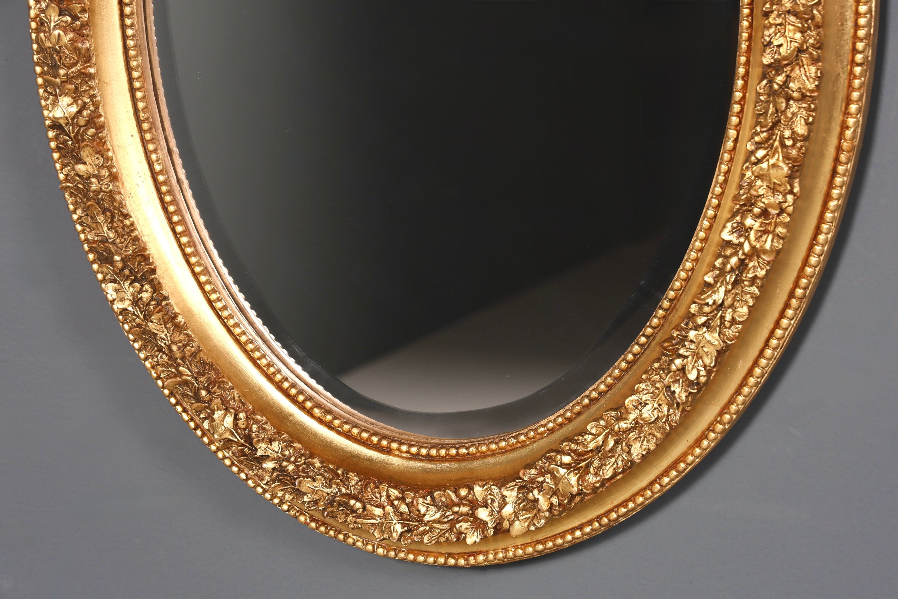 Miroir mural ovale élégant, de style baroque orné, avec des ornements dorés.