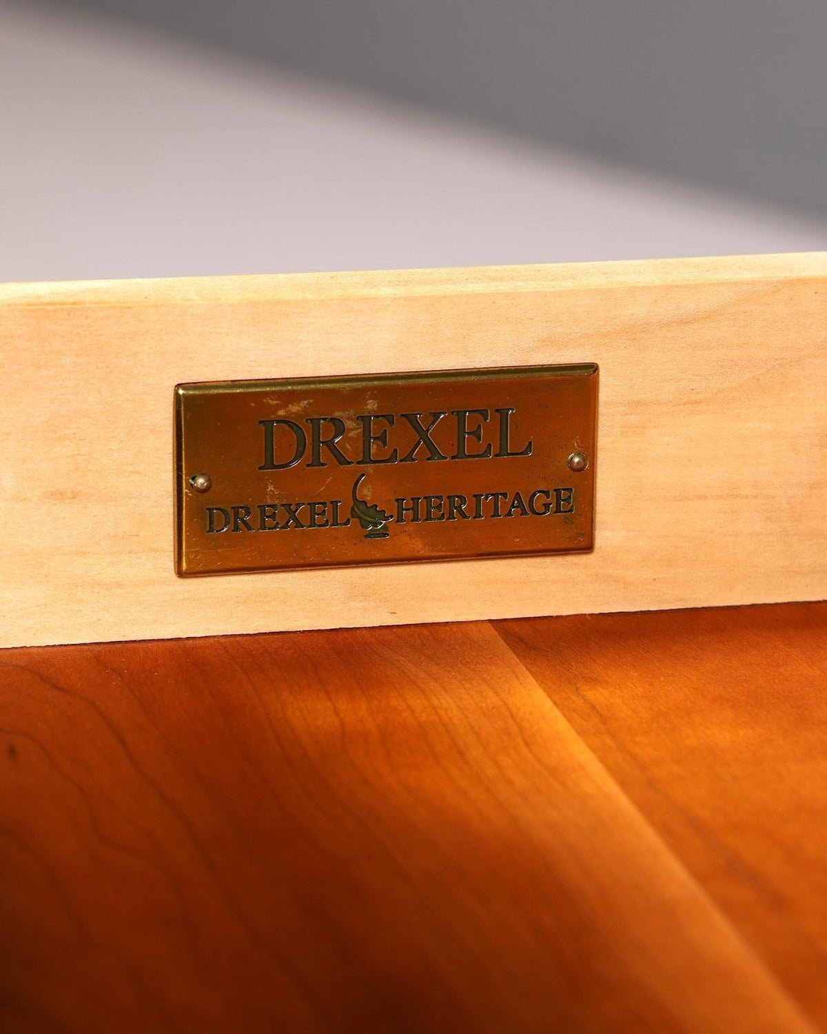 Messingschild mit Drexel Heritage Logo auf einer hellen Holzschublade von Hauptstadt Möblerei
