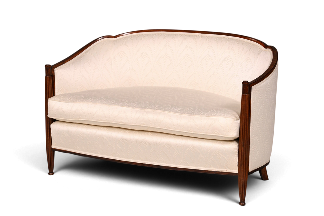 Hauptstadt Möblerei Art Deco Sofa mit hellem Polsterbezug, geschwungener Rückenlehne und geschnitztem Holzrahmen.